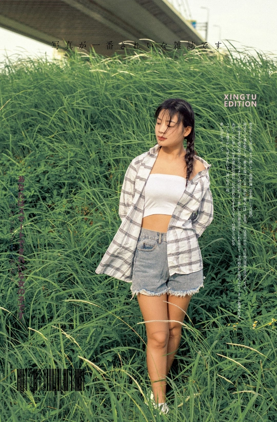 一位年轻女子在一片高草地上为拍照摆姿势
