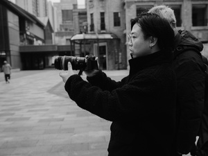 一个拿着相机在街上拍照的女人