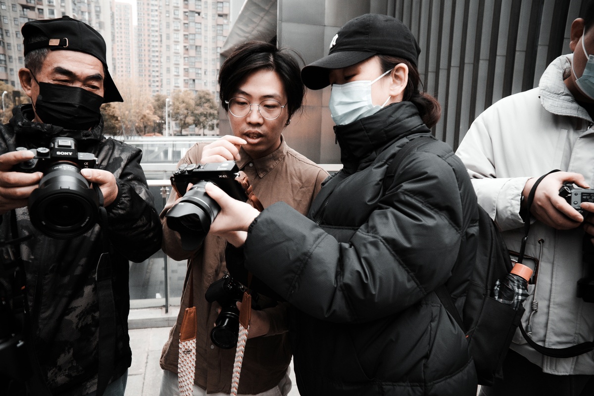 在城市里 一名戴着口罩的妇女站在其他戴着口罩、拿着相机的人面前