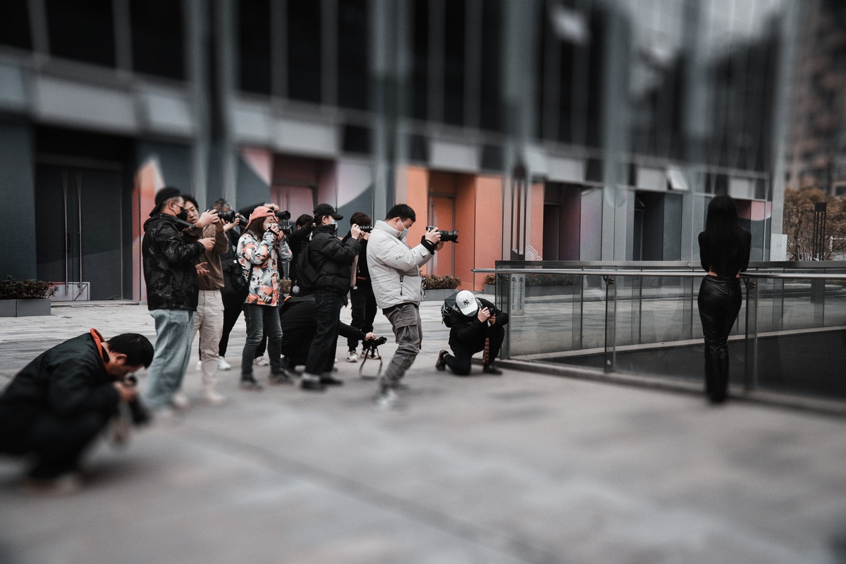 一名男子拿着相机在大楼外给一群人拍照