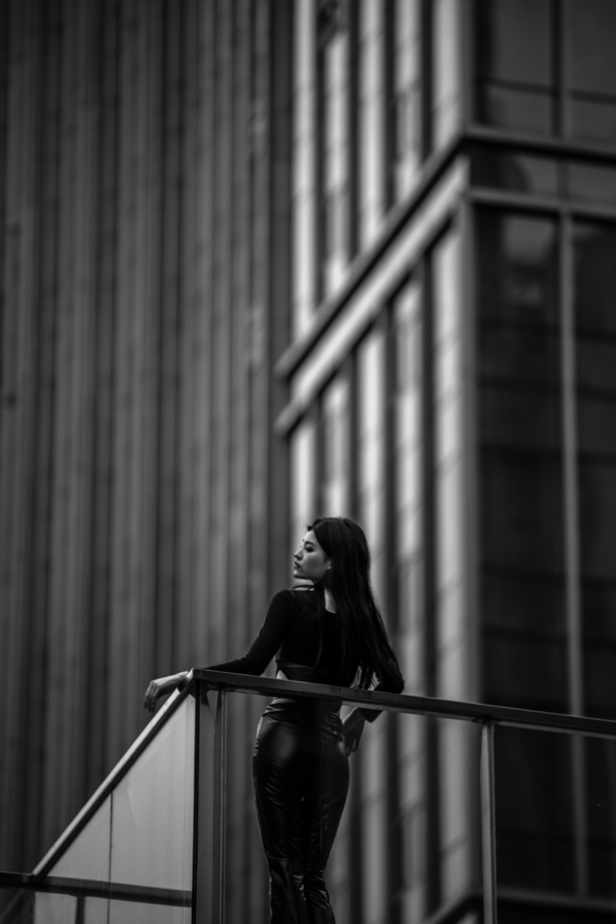 一位年轻女子站在一栋高楼前楼梯栏杆上的黑白照片
