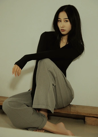 一个年轻女子穿着黑色裙子坐在地板上的长凳上