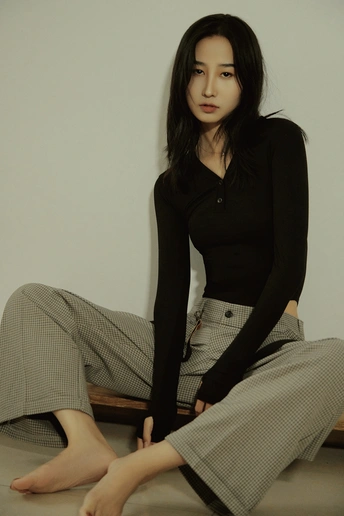 一个穿着黑色衬衫和黑色裙子的年轻女子坐在地板上