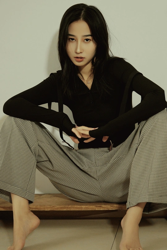 一位穿着黑色衬衫和长裙的年轻女子坐在长凳上