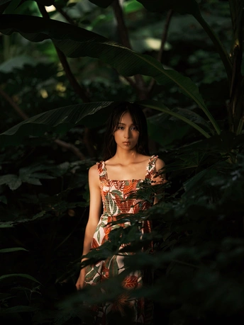 一位穿着连衣裙的年轻女子站在丛林中 在丛林中摆姿势