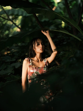 一个穿着连衣裙的年轻女子坐在森林或丛林中 头上有一片绿叶。