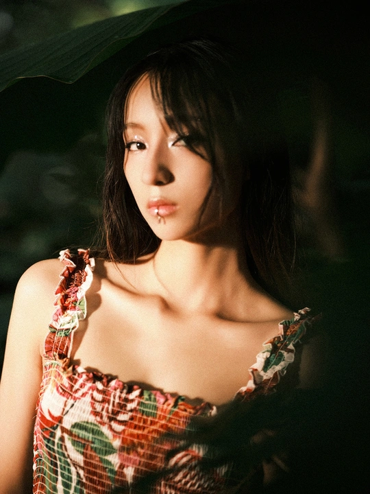 一位穿着连衣裙的年轻女子拿着一把绿色雨伞