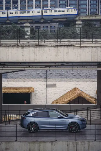 一辆停在桥下的汽车 一辆火车从它上方经过。