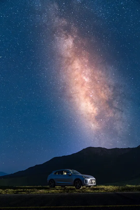 夜空下 山边停着一辆汽车 星星闪烁。