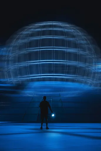 站在夜晚照亮的天蓝色圆顶前面的一个男人
