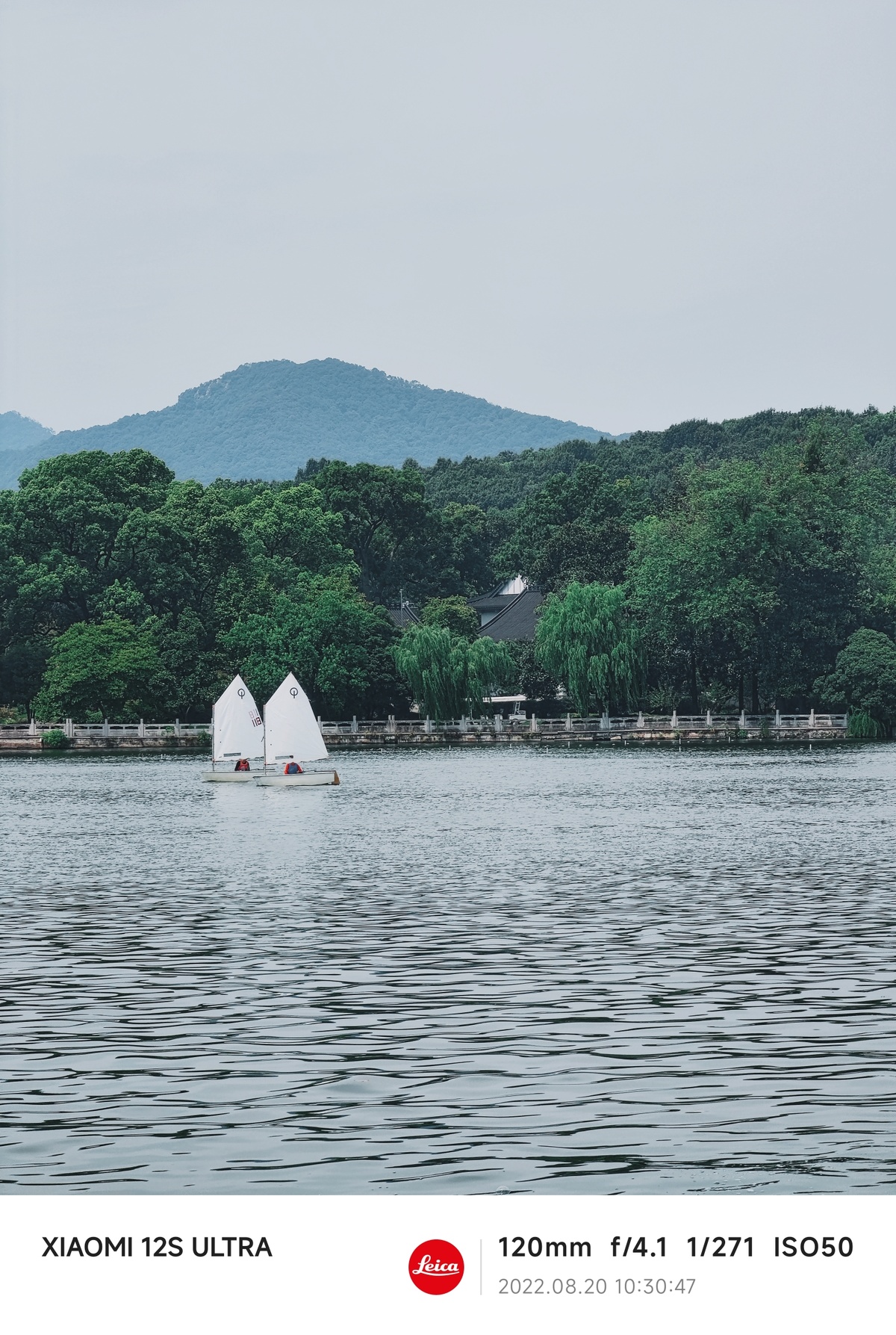 背景是山脉的水体 前景是一艘白色帐篷的小船