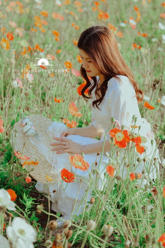 一位穿着白色连衣裙的年轻女子在草地上采摘野花