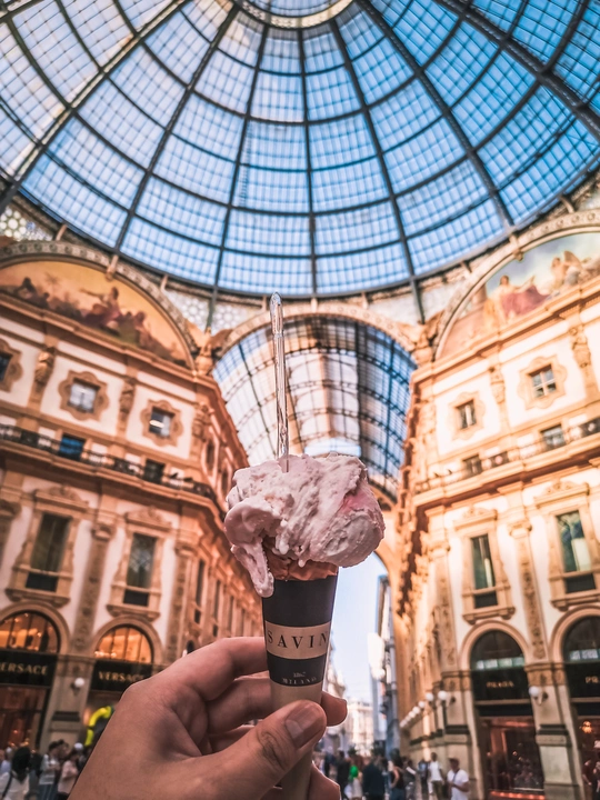 在建筑物前拿着冰淇淋筒的人