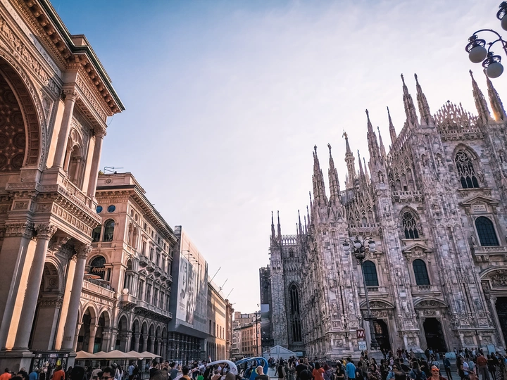 一群撑着雨伞的人走在哥特式大教堂前的街道上