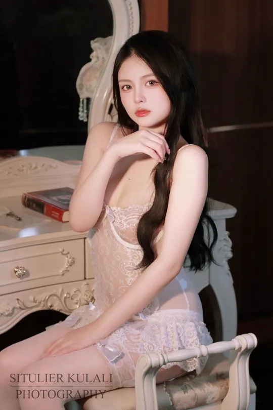 一个穿着白色连衣裙的年轻女子坐在白色椅子上
