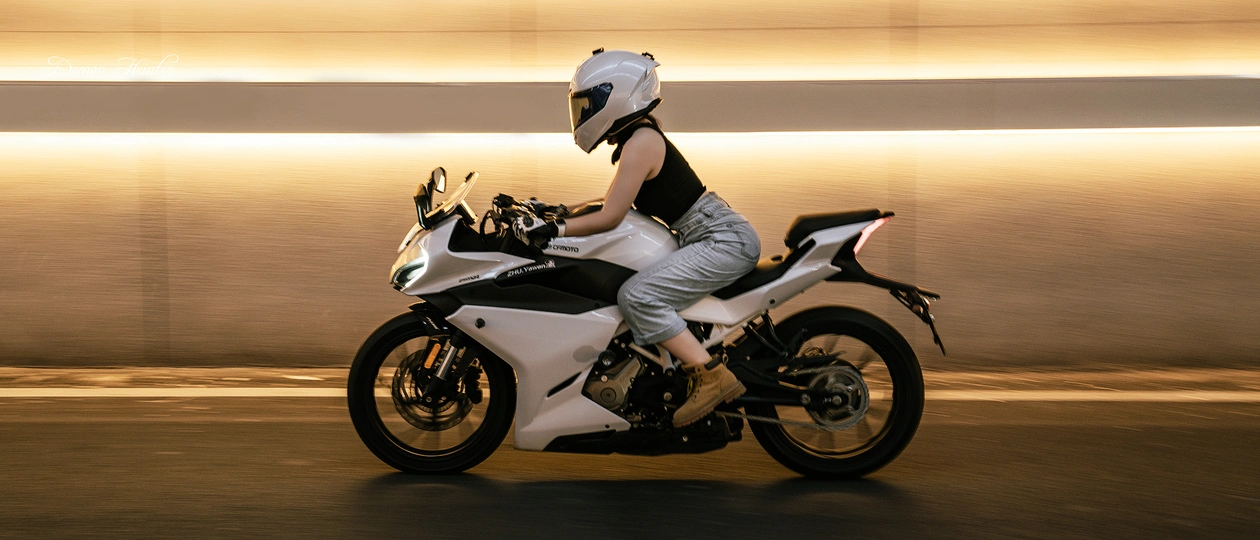 一个戴头盔的男子骑摩托车 后面跟着一个女子。