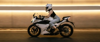 一个戴头盔的男子骑摩托车 后面跟着一个女子。