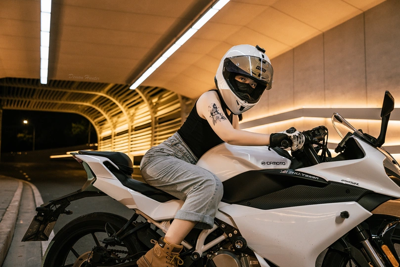 一个戴黑色头盔的男子坐在白色摩托车上 停在停车场