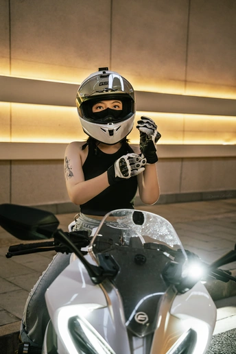 一个戴黑色头盔和手套的年轻女子坐在摩托车上
