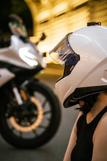 一位戴白色头盔的女人站在一辆摩托车旁边