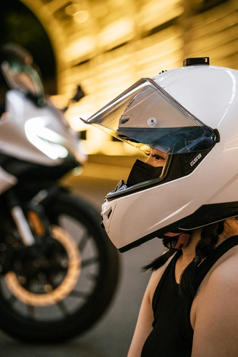 一位戴白色头盔的女人站在一辆摩托车旁边