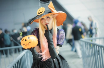一个穿着巫婆服装的年轻女子抱着一个南瓜。