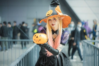 一个穿着巫婆服装的年轻女子抱着一个南瓜。