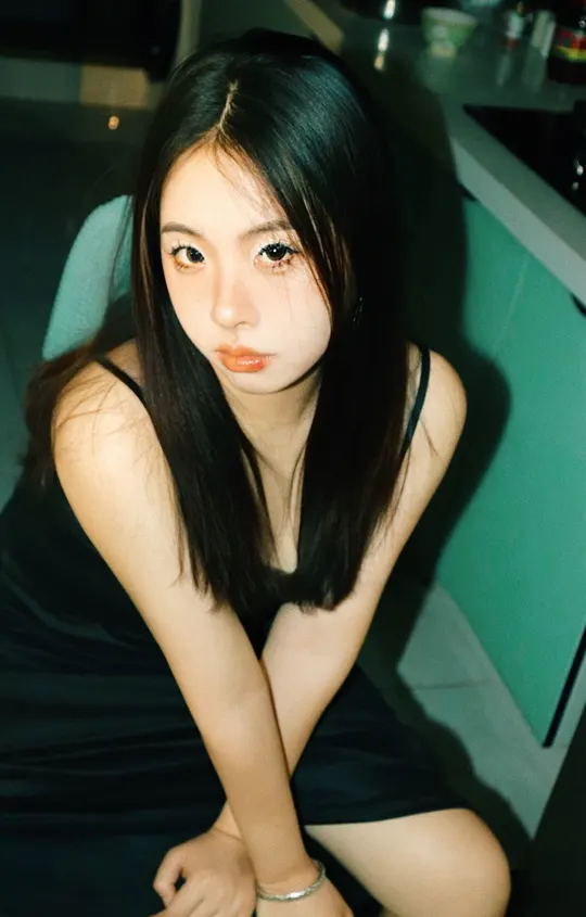 一个穿着黑色连衣裙的女人坐在地板上的椅子上