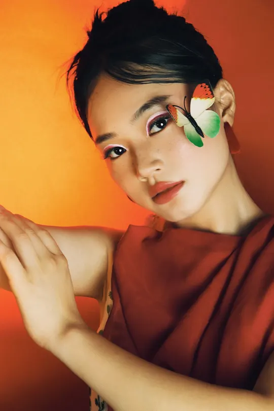 一位穿着红橙色衣服的女性 双手捂住脸