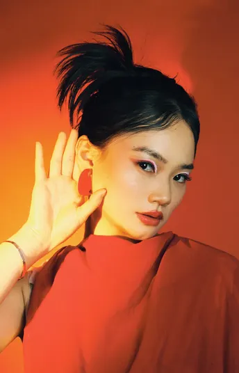 一位穿着红裙子的年轻女子 把手举到耳边