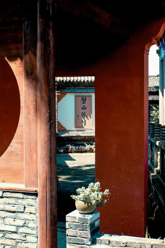 一个带红门的庭院 有柱子和花。