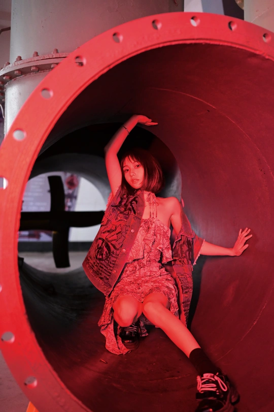一个年轻女子穿着红色连衣裙坐在一个通道或管子里。