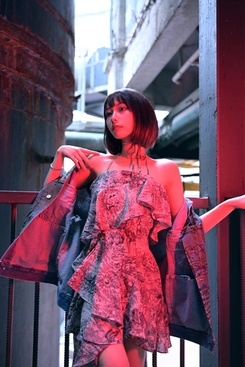 一个穿着红色连衣裙的年轻女子倚靠在围栏上。